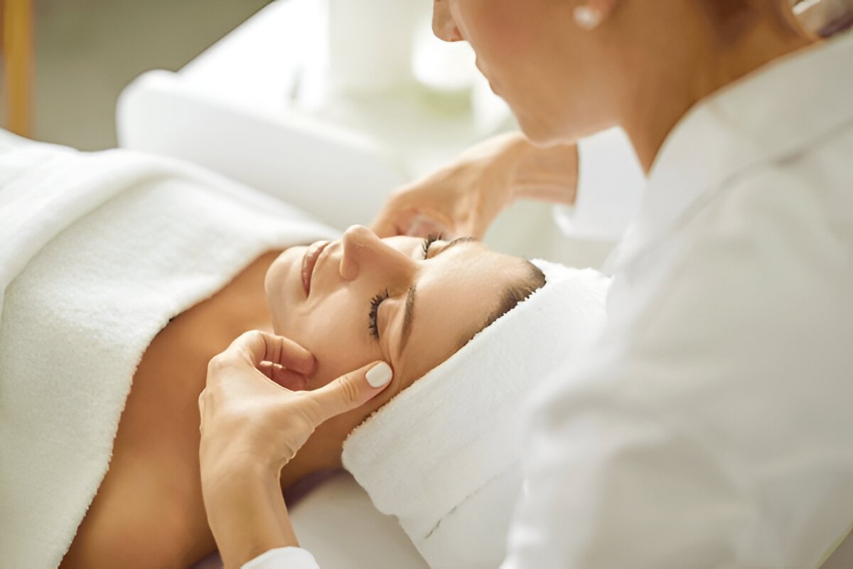 woman lying with closed eyes and having face or head massage