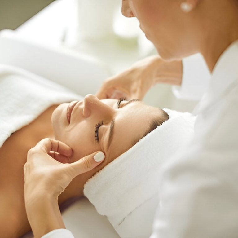 woman lying with closed eyes and having face or head massage
